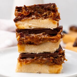Millionaire shortbread stacked on top of each other in white dish.