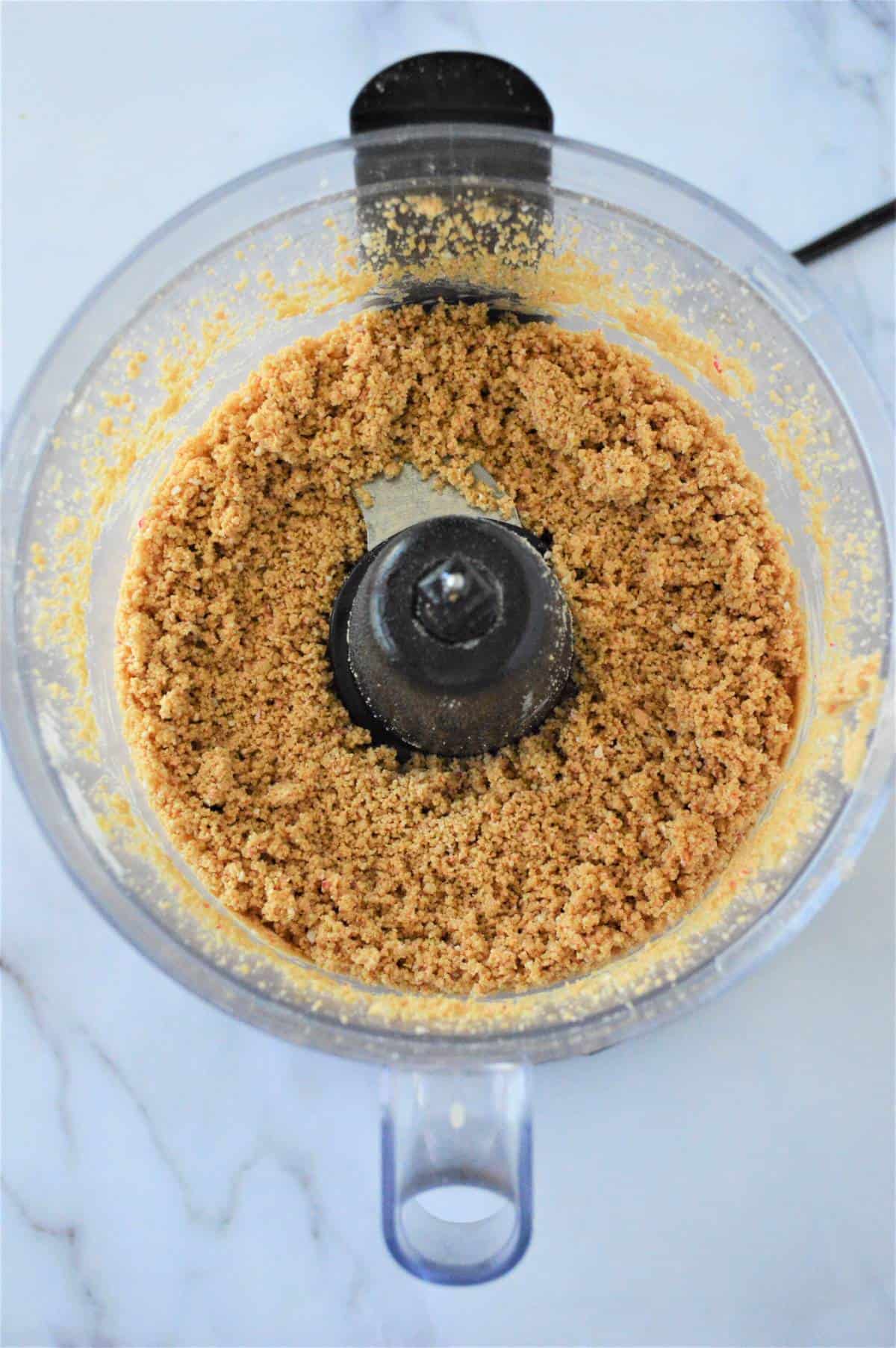 A food processor filled with a mixture of protein-rich ingredients for making Protein Balls.