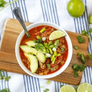 No bean chili being served in a bowl with lime and avocado.