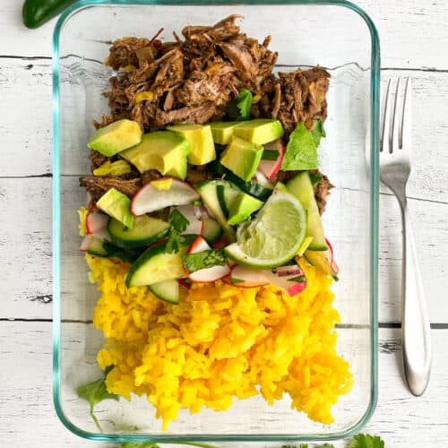 Barbacoa beef, yellow rice, and avocado in a meal prep container.