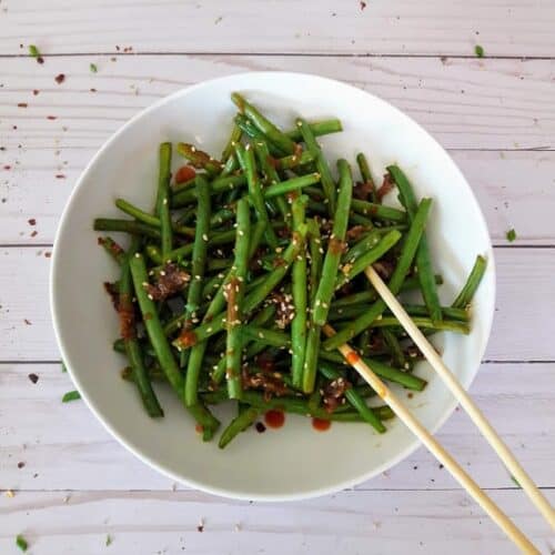 Chinese spicy green beans on a plate with chop sticks.