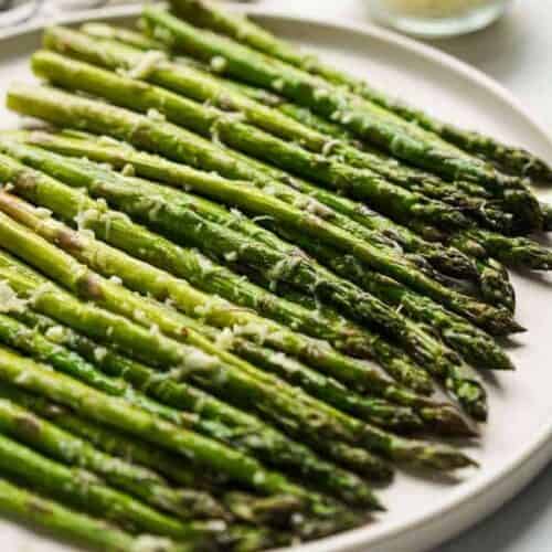 Roasted asparagus being served on a plate.
