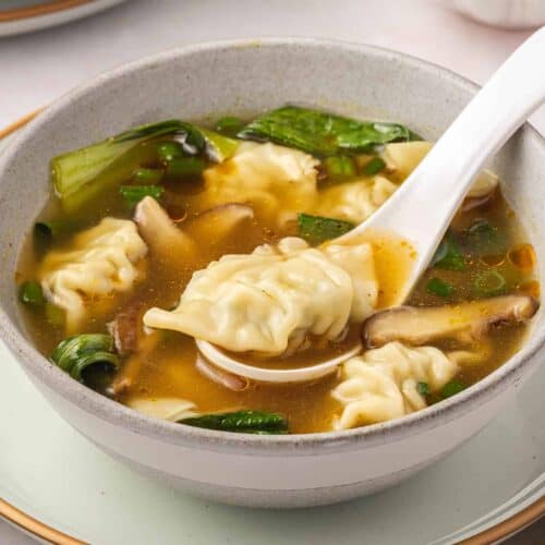 Wonton soup in a bowl with a spoon.