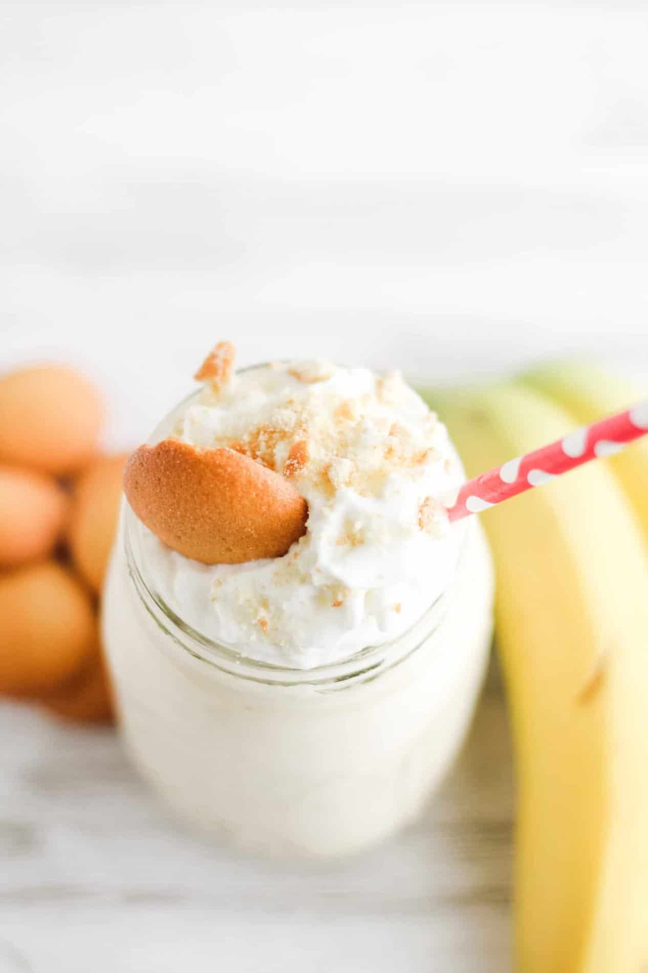 Banana protein shake in glass with whipped cream and a cookie. 
