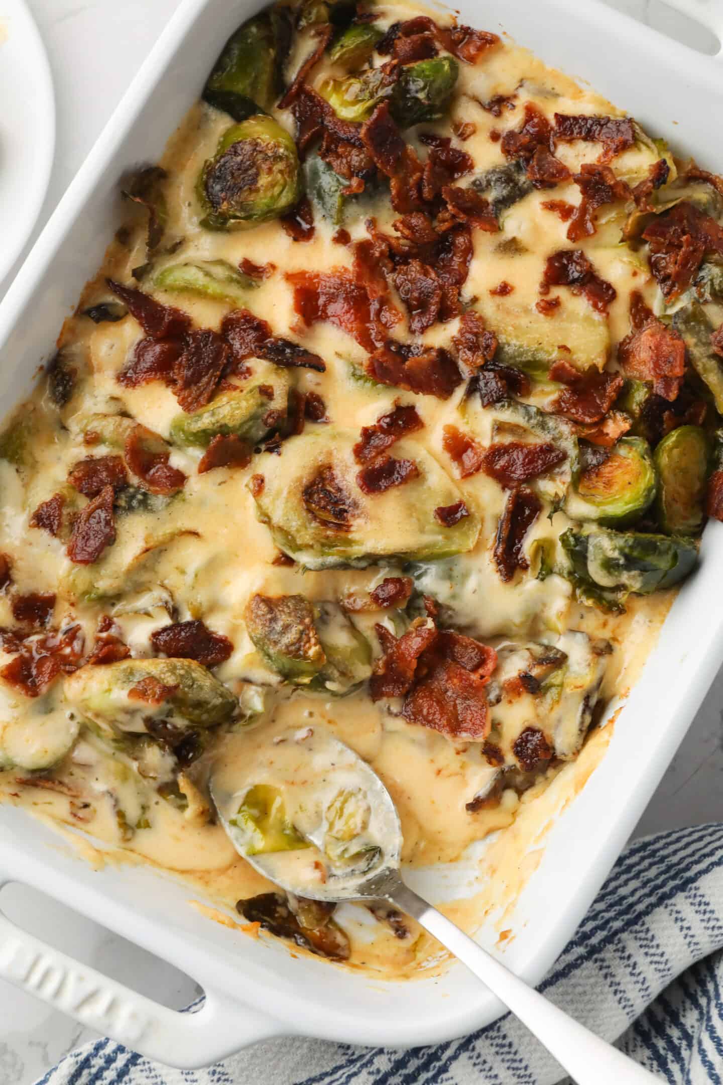 Roasted Brussel sprouts with cream sauce in a baking dish and topped with bacon. 
