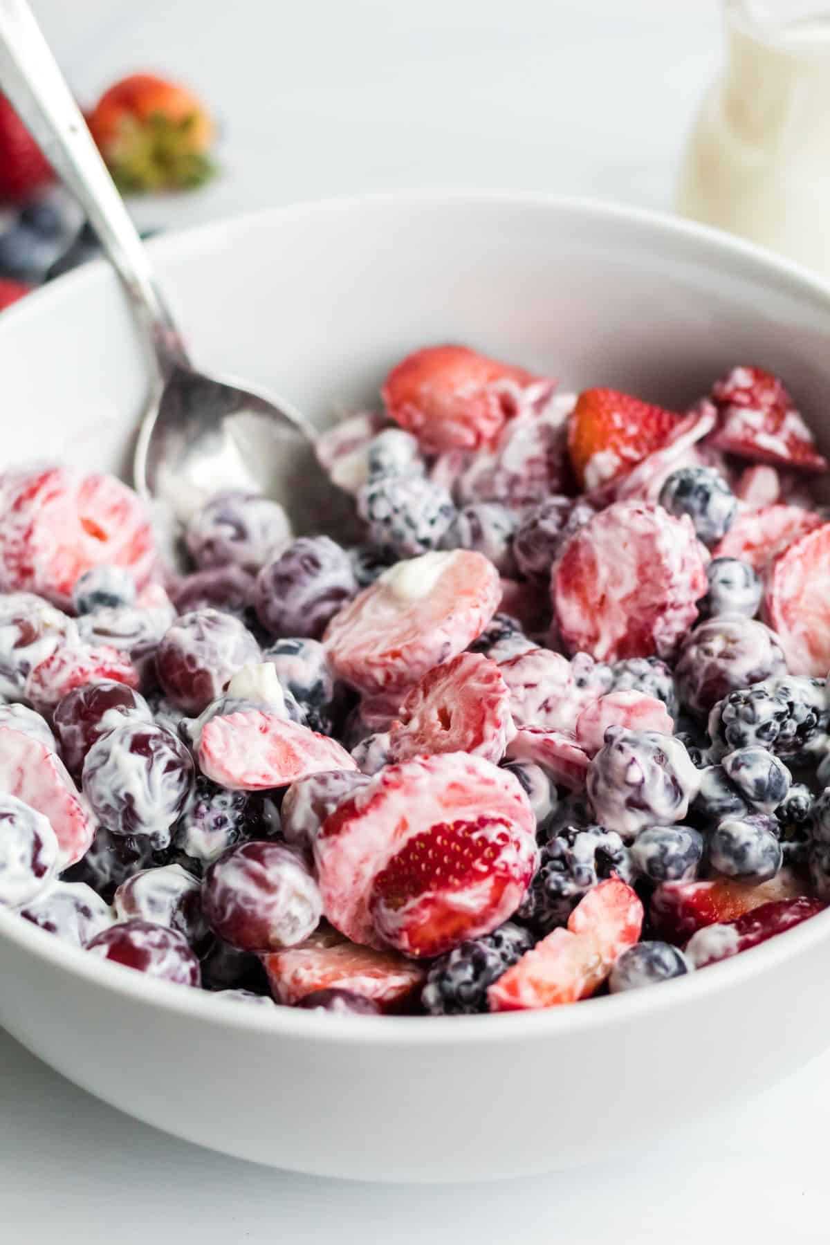 Creamy fruit salad with yogurt being served in a bowl. 