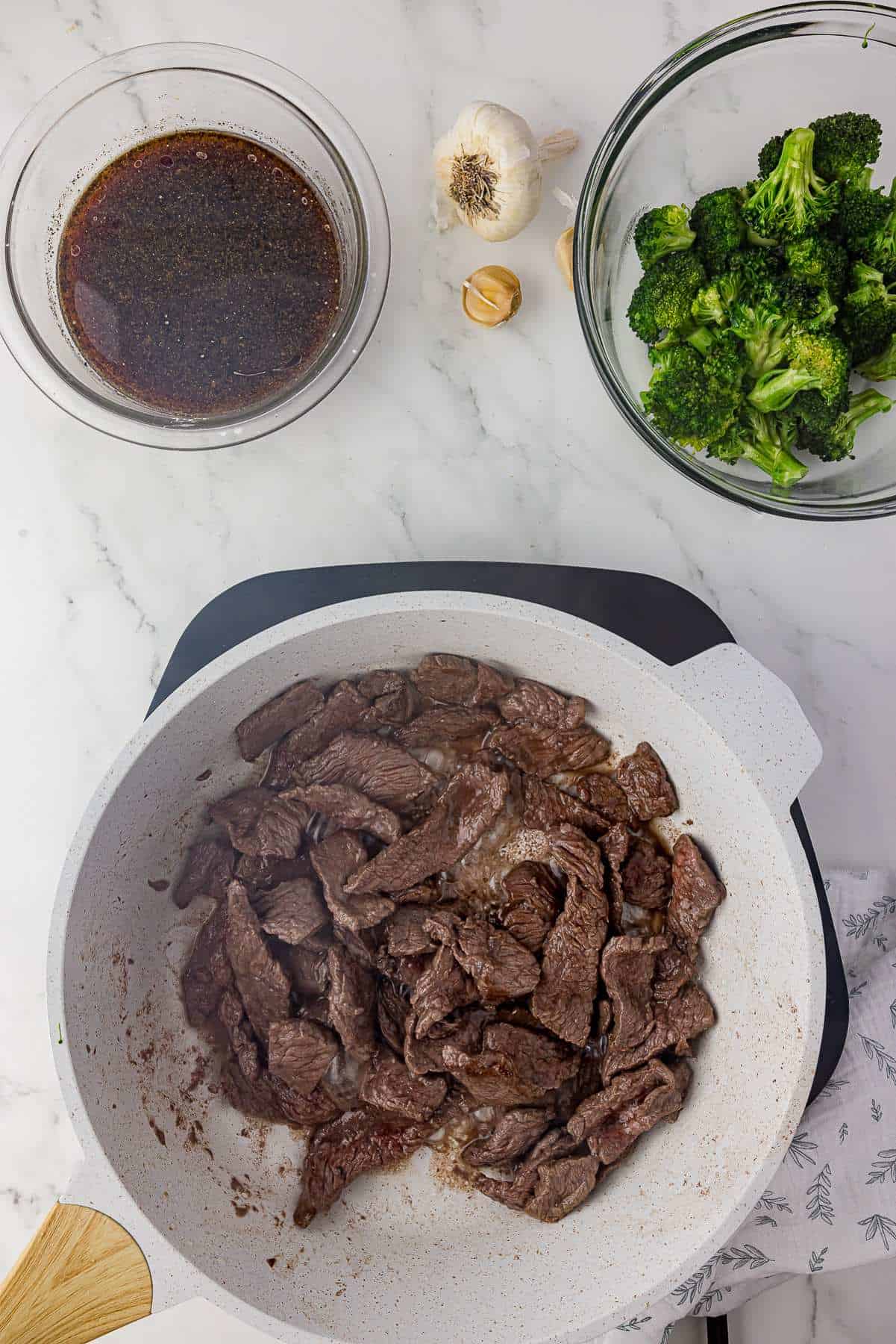 Beef being stir-fried in a pan. 