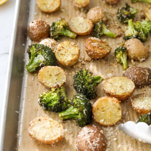 Roasted broccoli and potatoes on a baking sheet.