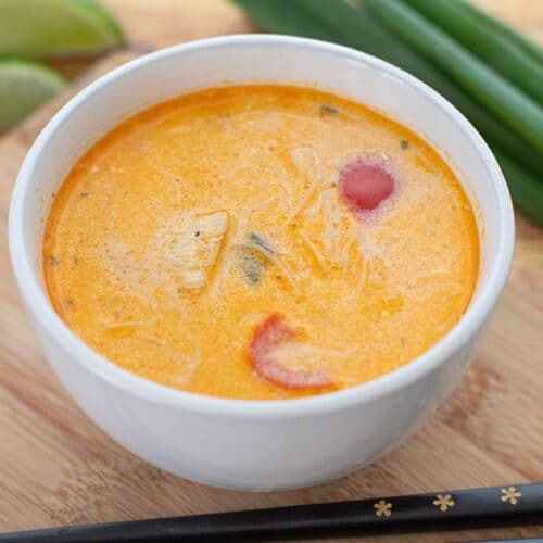 Thai red curry soup being served in a bowl.