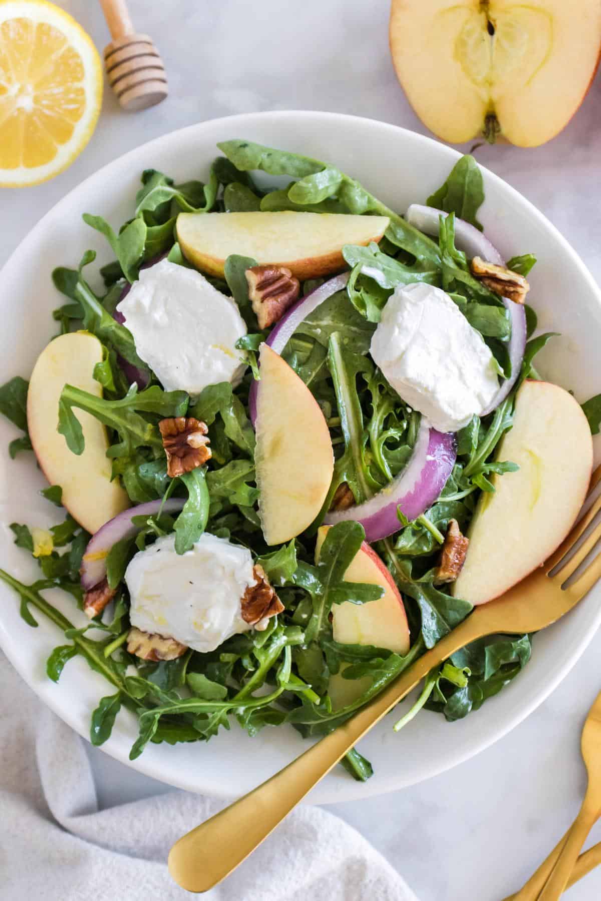 Arugula Apple Goat Cheese Salad being served in a bowl. 