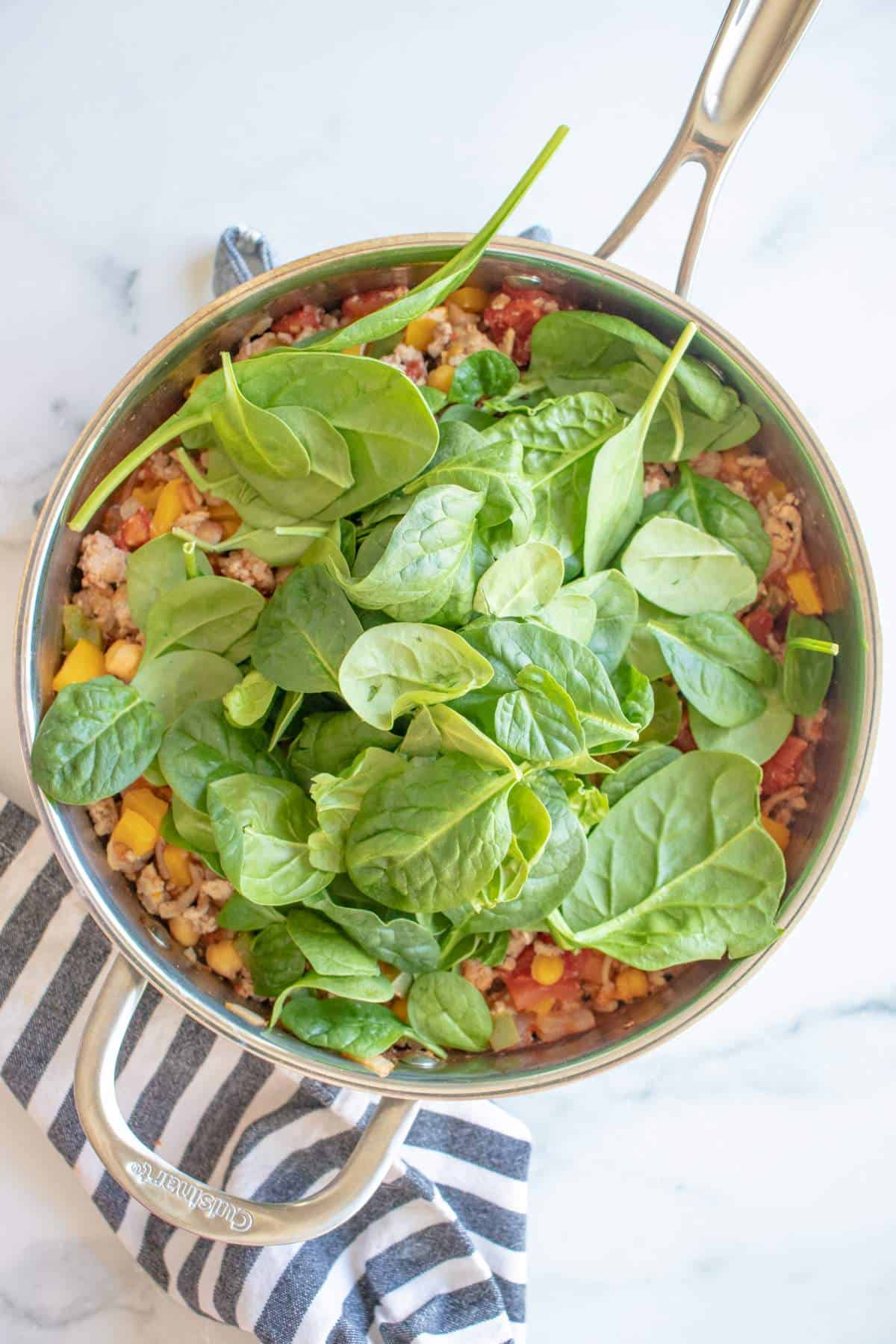 Ground turkey, veggies, and spinach being cooked in a pan. 