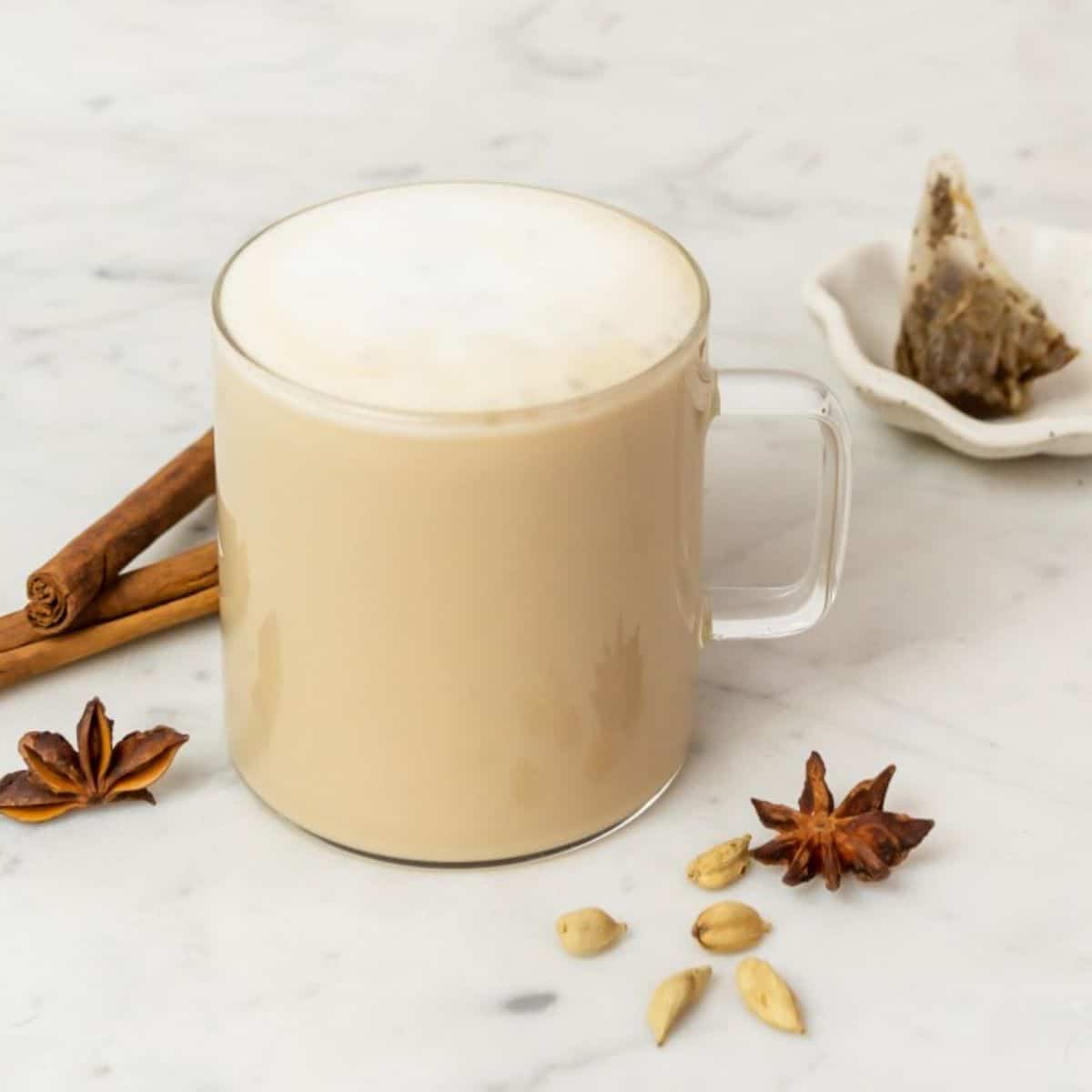 Chai tea latte in glass mug with cinnamon stick.