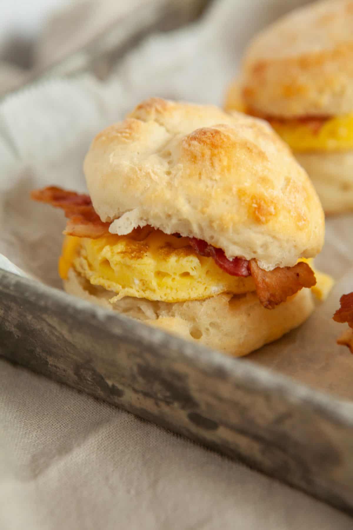 Bacon egg and cheese biscuit on a baking sheet.  
