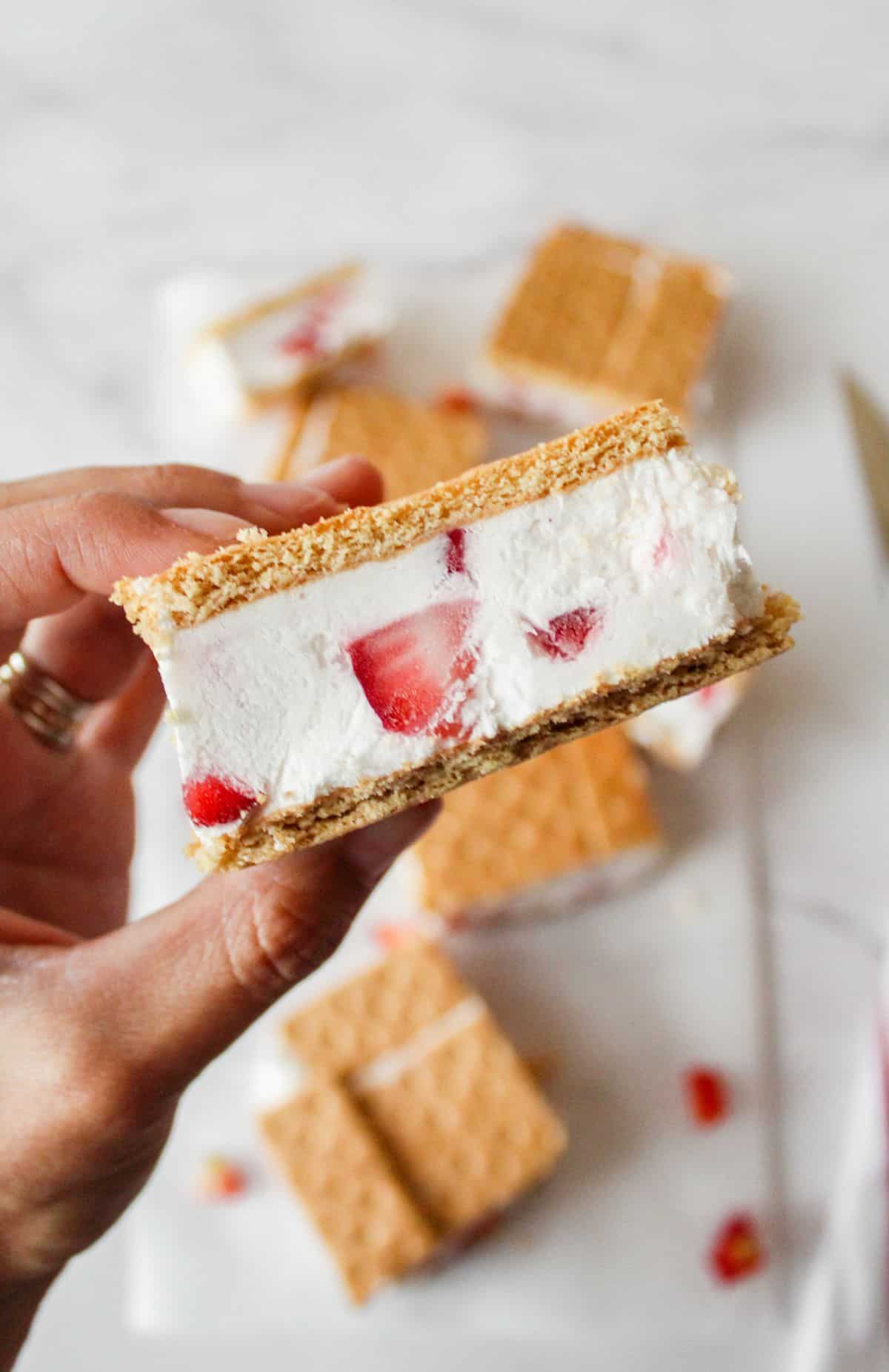 Strawberry ice cream sandwich. being held by a hand. 