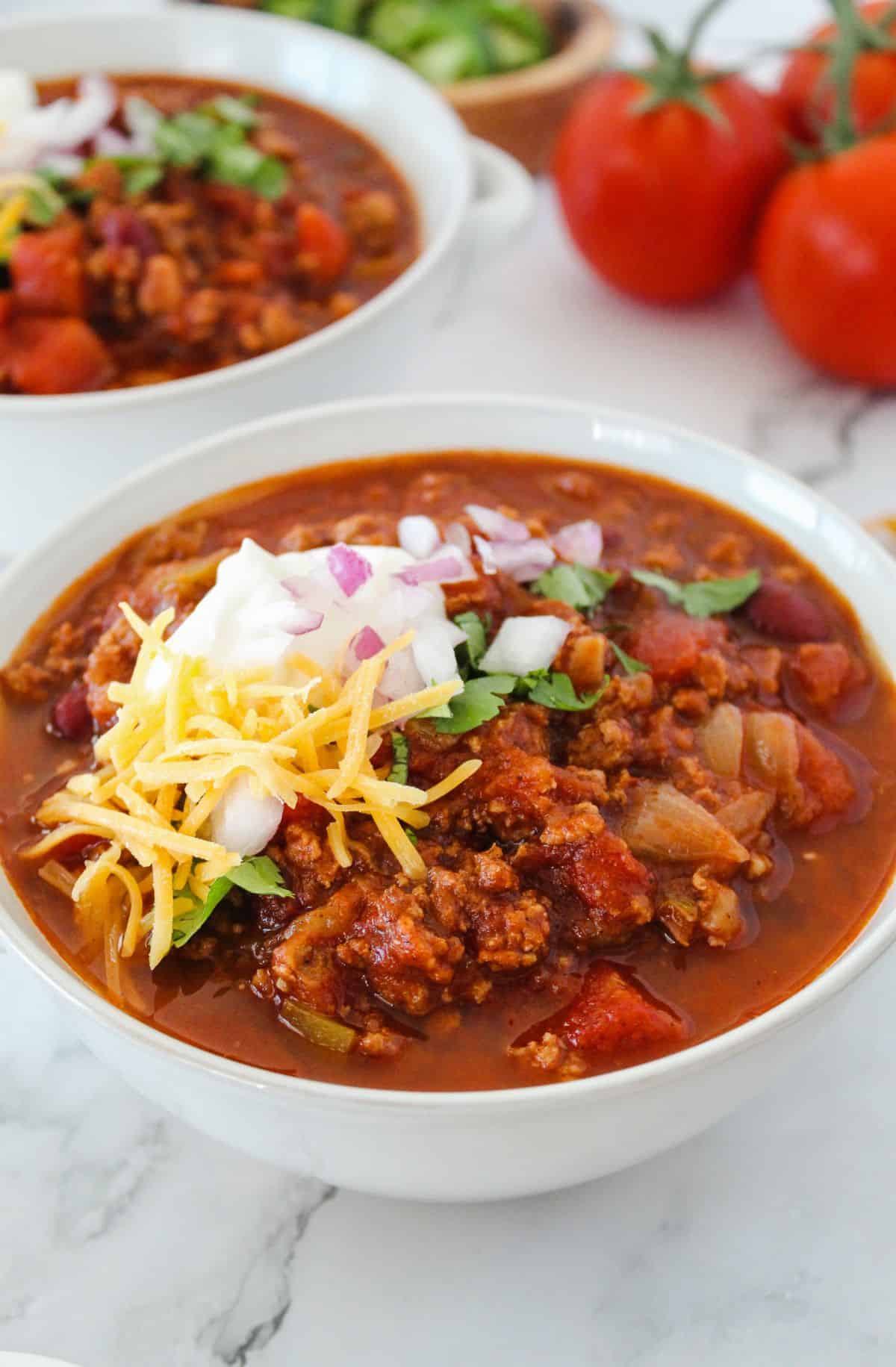 High protein turkey chili in a white bowl with toppings. 
