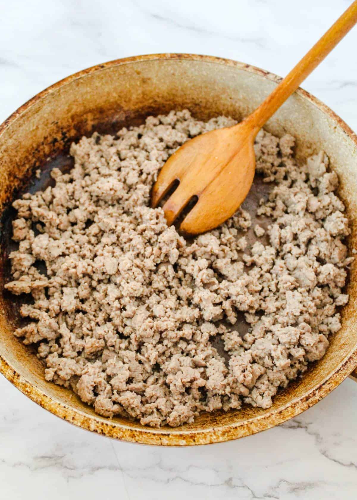Ground turkey being browned in a skillet. 
