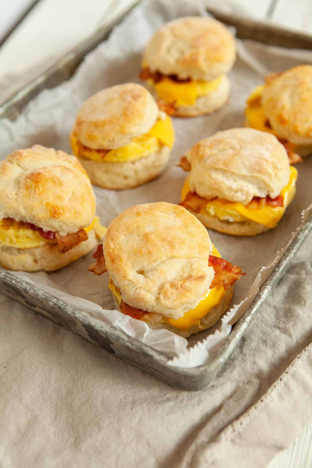 Bacon, egg, and cheese biscuits on parchment lined baking sheet. 