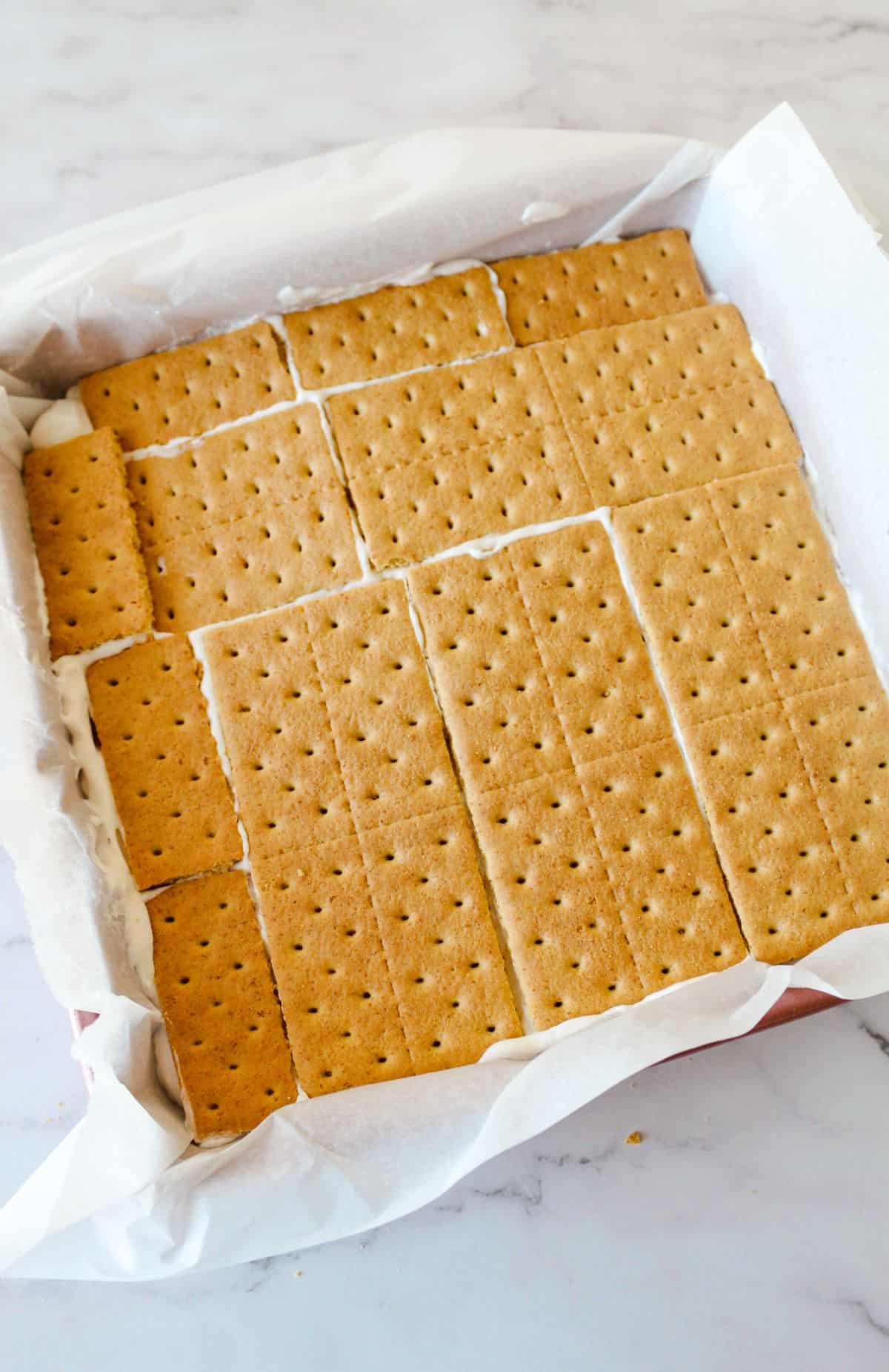Remaining graham crackers being put on top of ice cream sandwiches. 