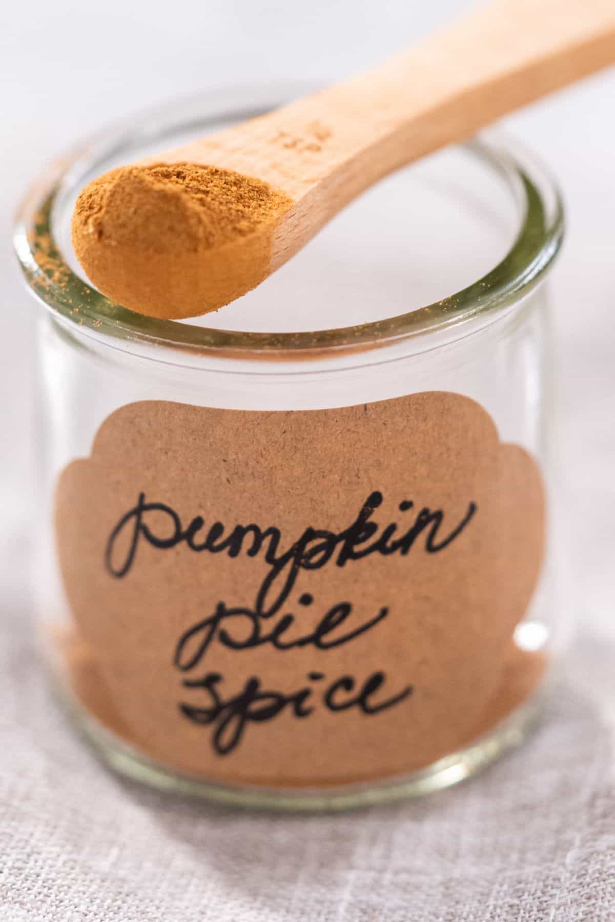 Homemade pumpkin pie spice in jar being spooned out. 