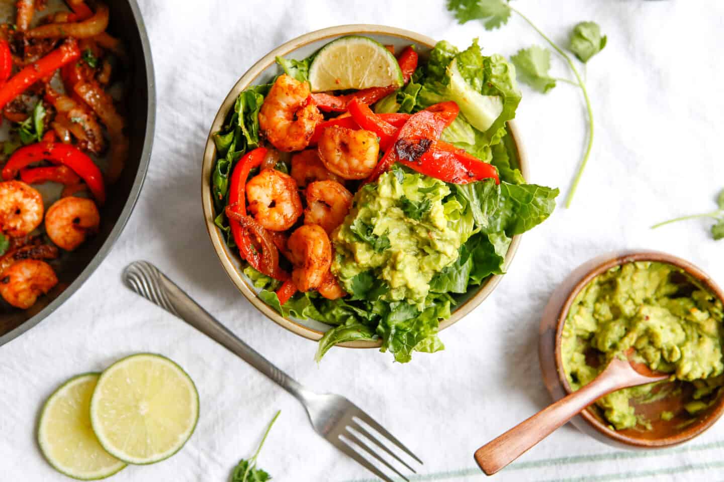 Shrimp fajita mixture served over a bed of lettuce with avocado. 