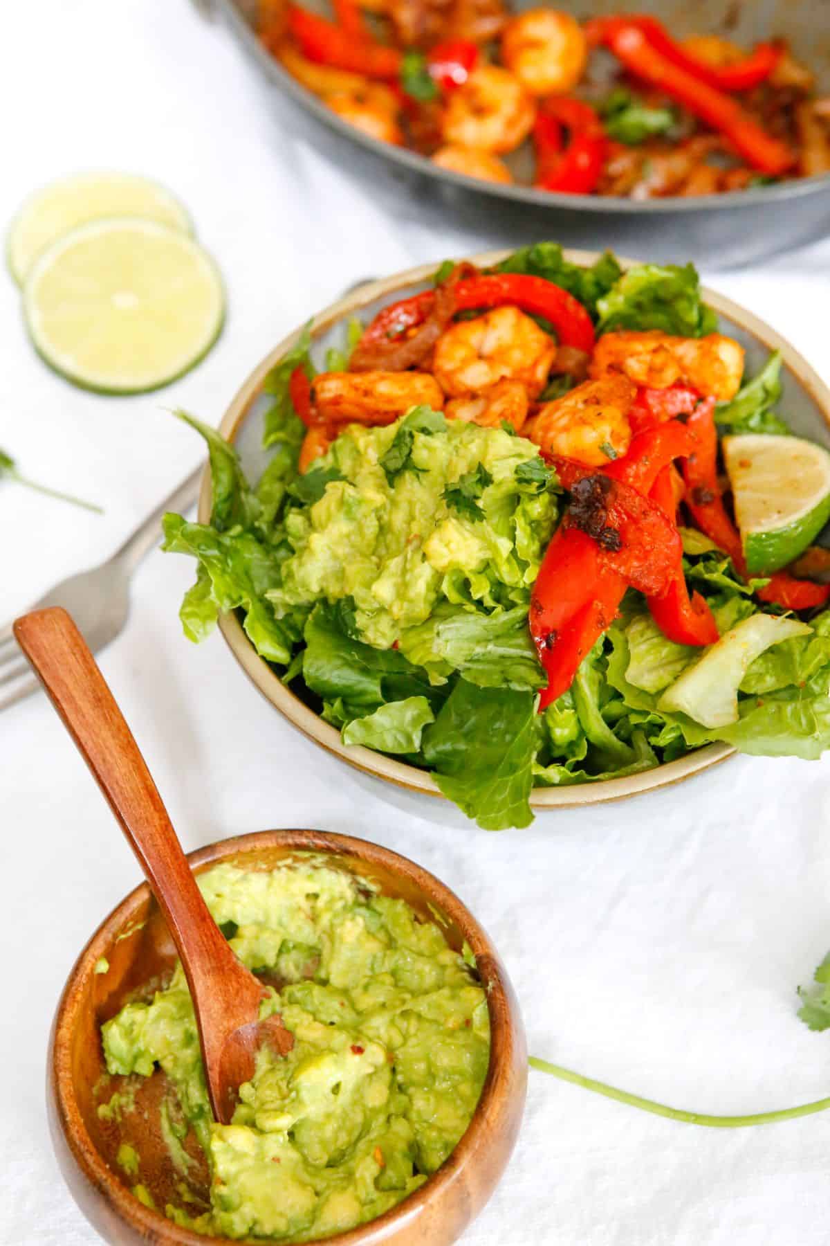 Shrimp fajita bowls being served in a bowl with avocado. 