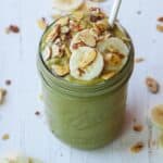 Mango spinach smoothie in a mason jar with a straw.