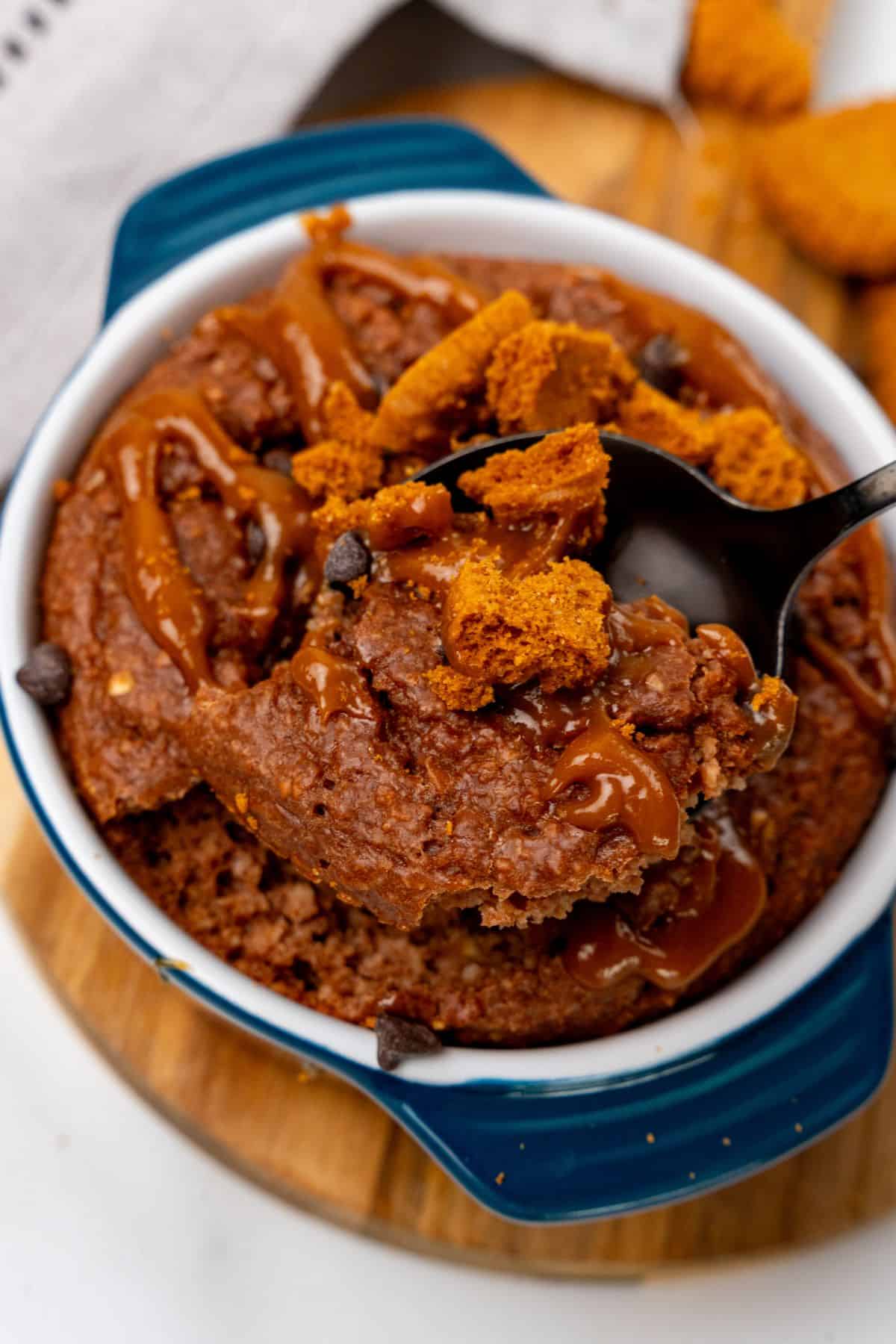 Biscoff baked oats in a ramekin dish with spoon being dished out. 