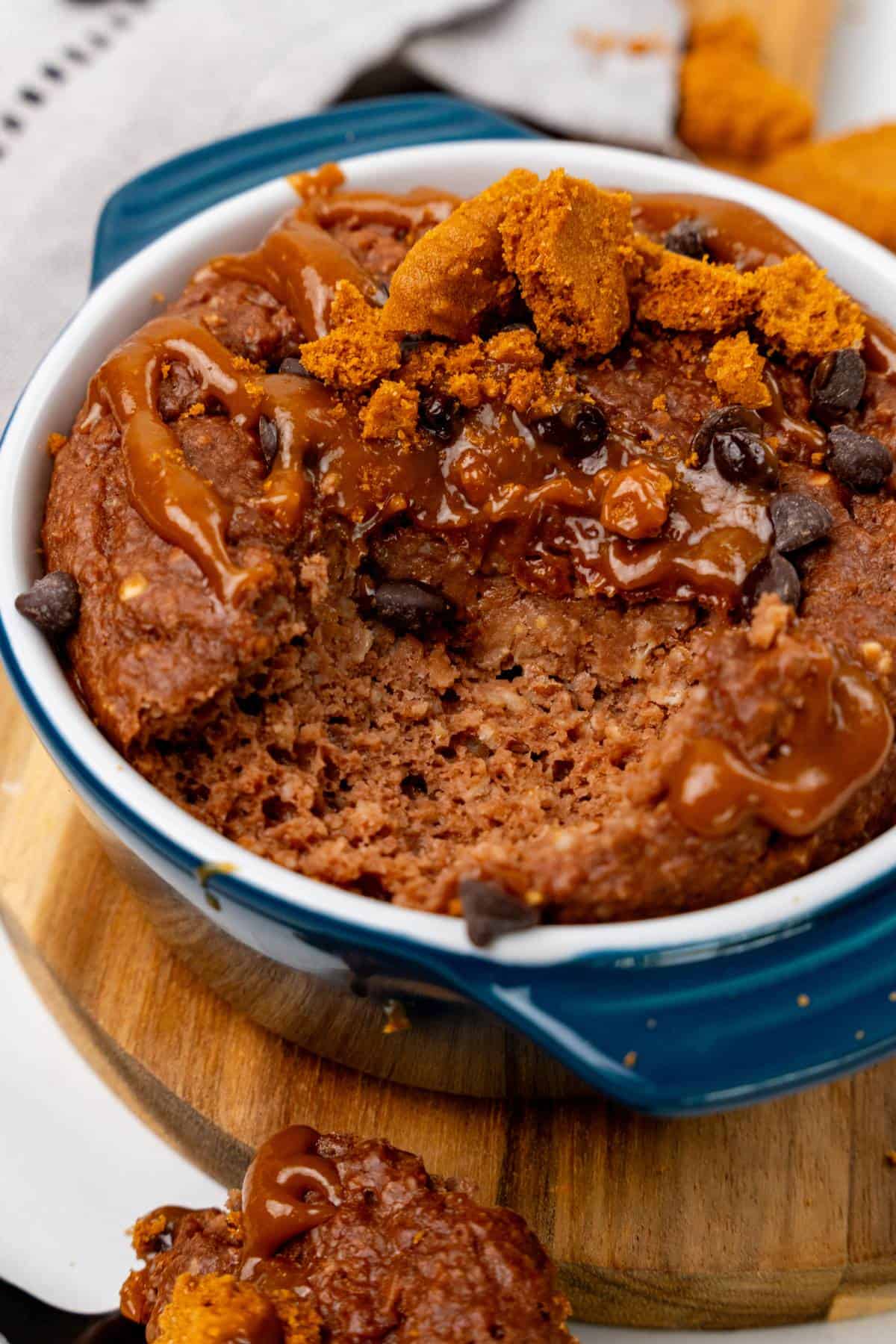 Biscoff baked oats in a ramkein dish with toppings and a bite taken out of it. 
