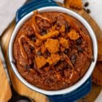 Biscoff baked oats in ramkein dish with toppings on a cutting board.