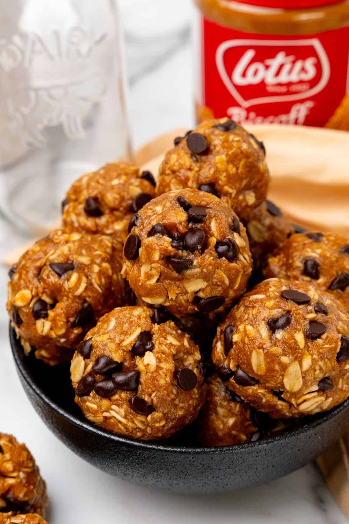 Biscoff protein balls in a bowl with a jar of Biscoff. 