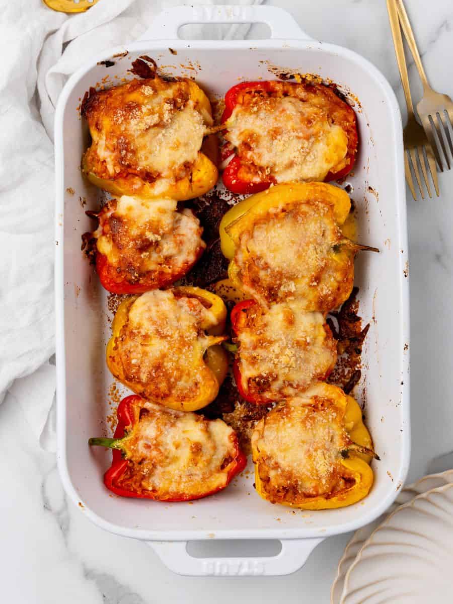 Stuffed peppers in a white baking dish.