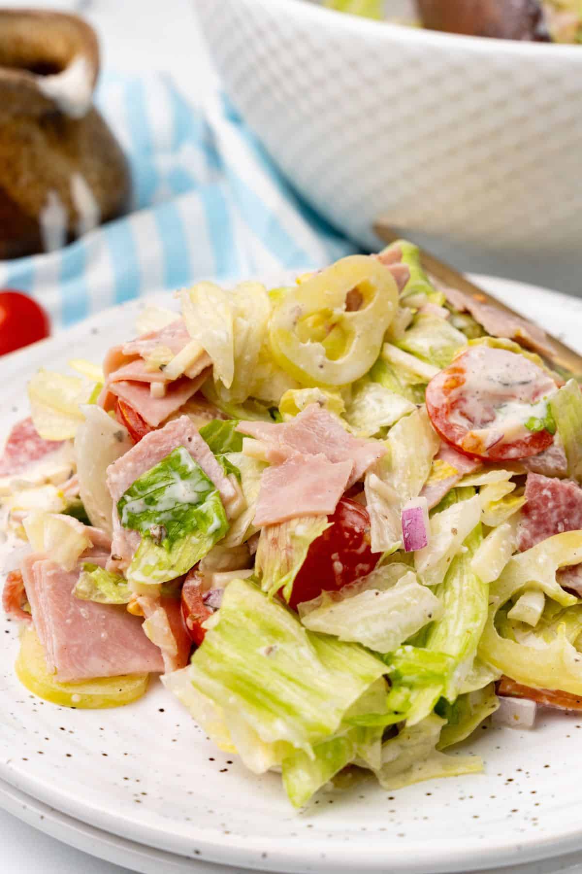 A grinder salad with ham, salami, and tomatoes.