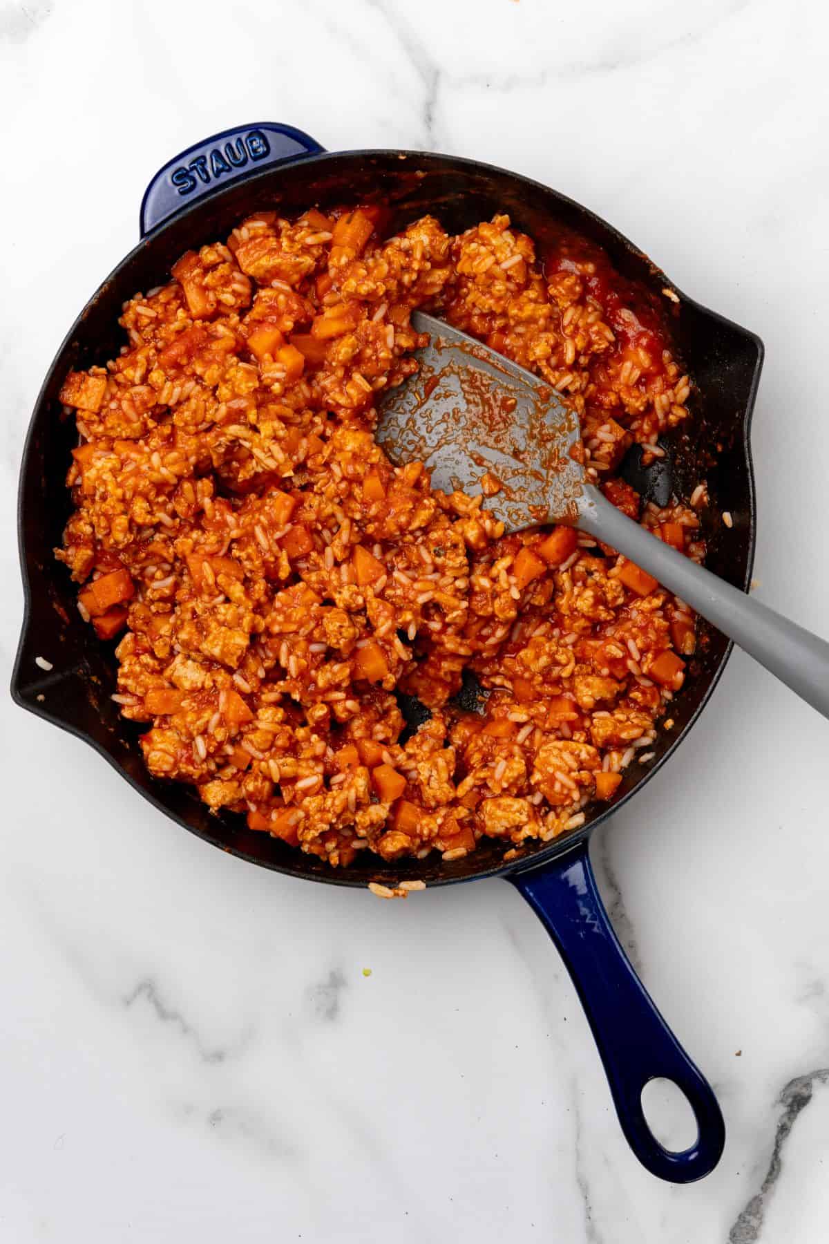 A pan filled with rice, ground chicken, carrots, and marninara sauce. 
