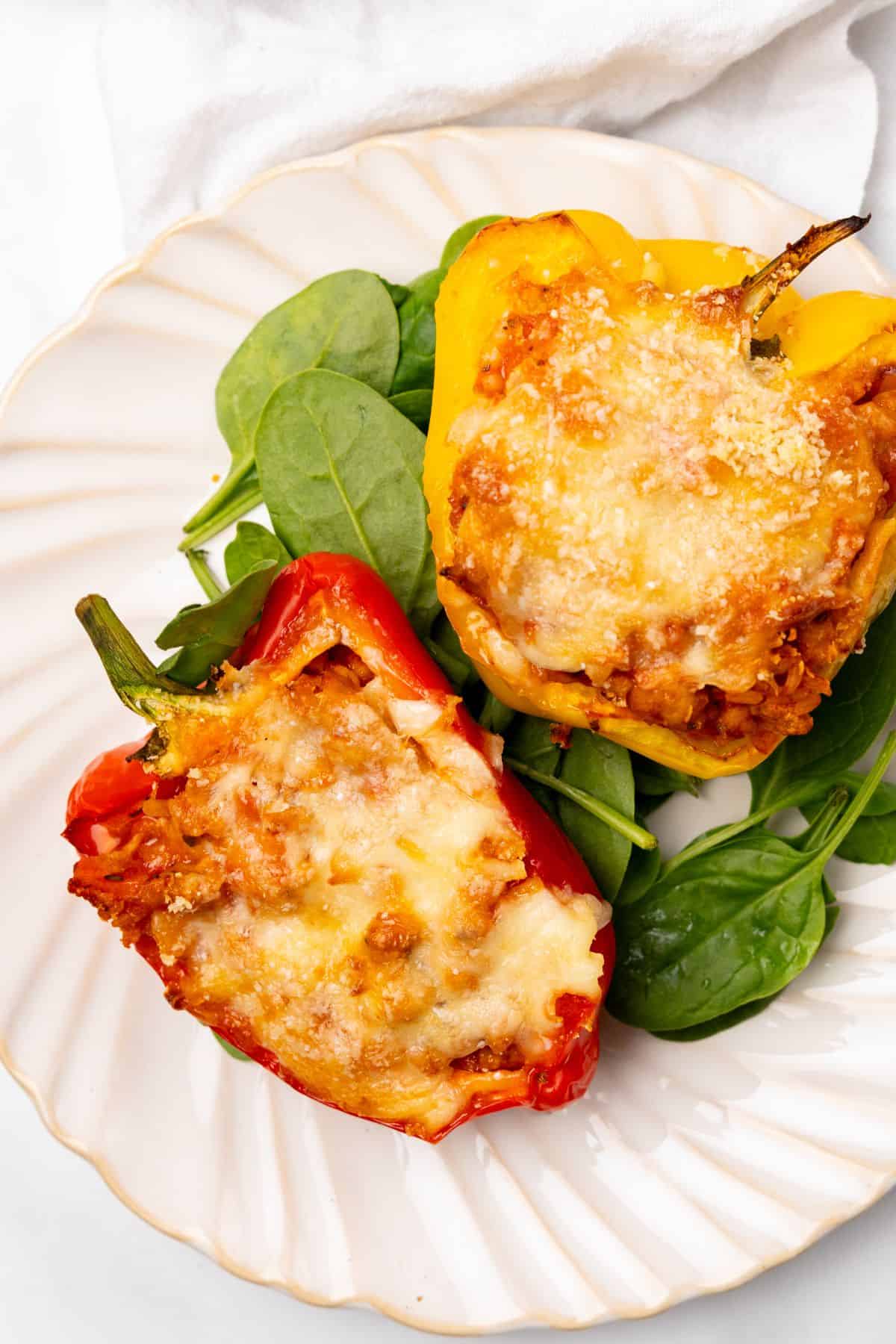 Ground chicken stuffed peppers over  spinach on a plate.