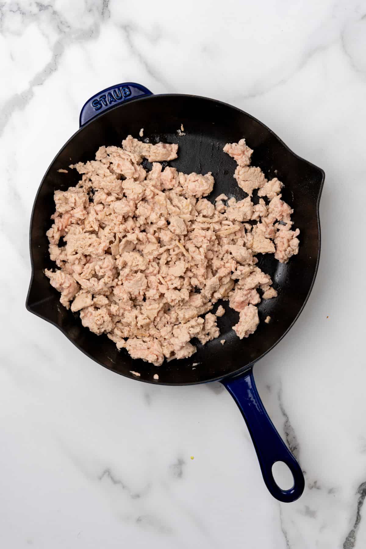 A pan with ground chicken being cooked. 