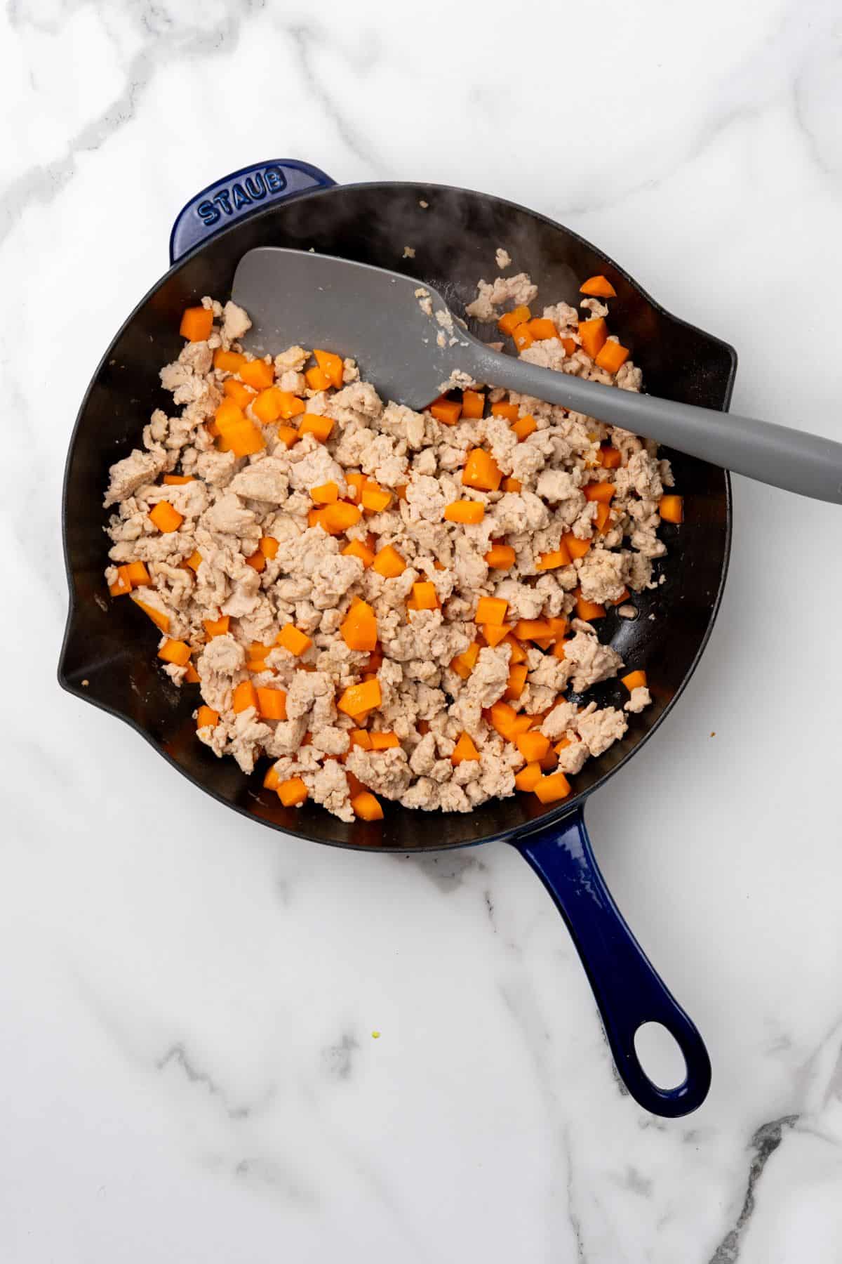 A pan of ground chicken  and carrots.