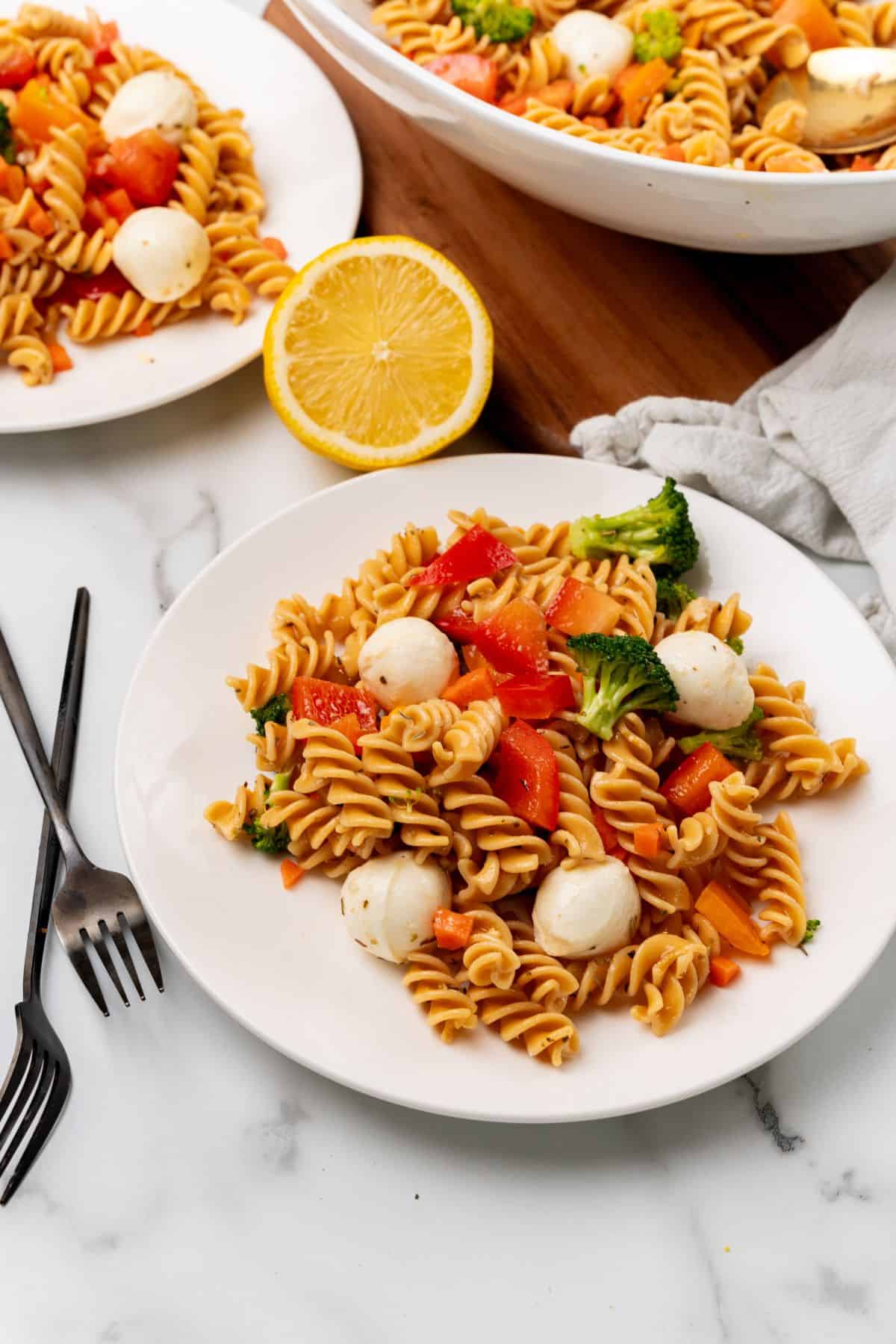 A protein-packed pasta salad featuring chicken and vegetables on a white plate. 