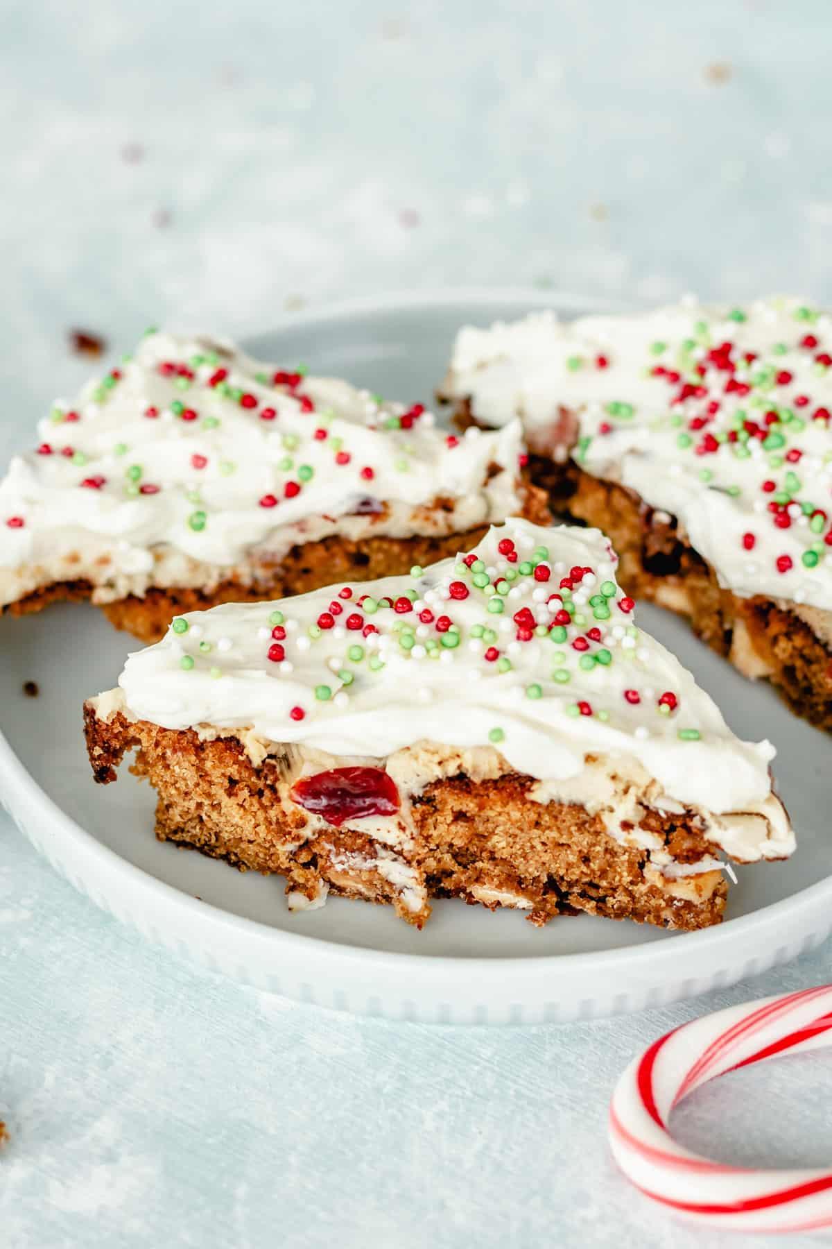A piece of cranberry bliss bars with frosting and candy canes on a plate.