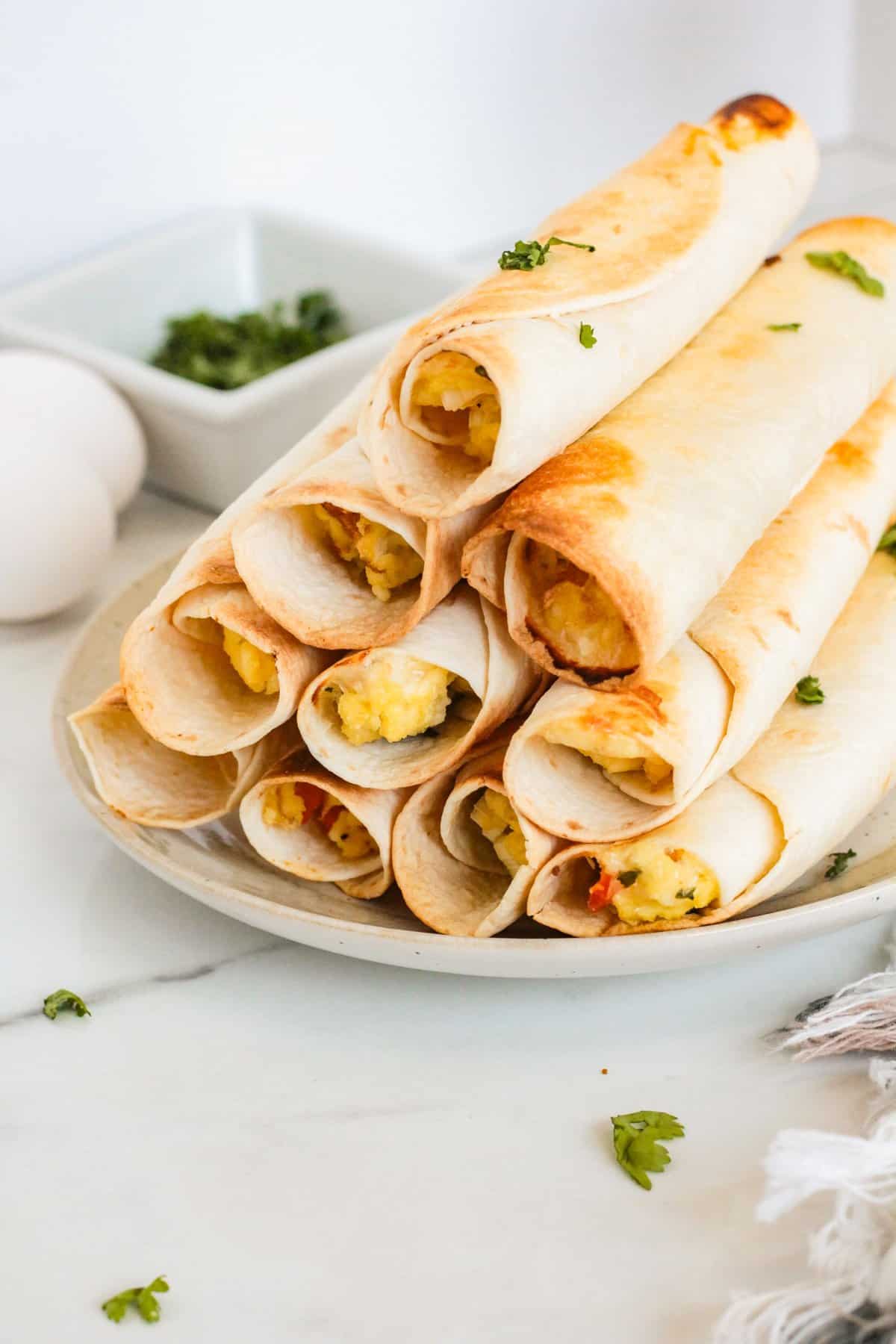 Breakfast taquitos arranged on a white plate. 