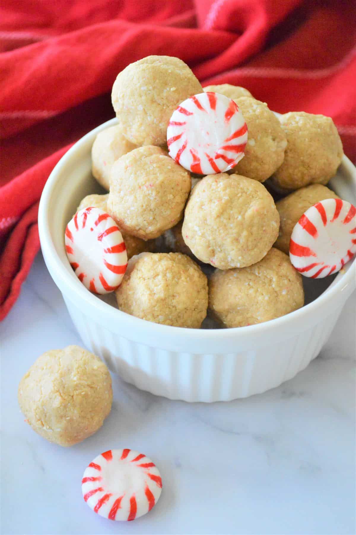 A white bowl filled with peppermint candy and Christmas Protein Balls.