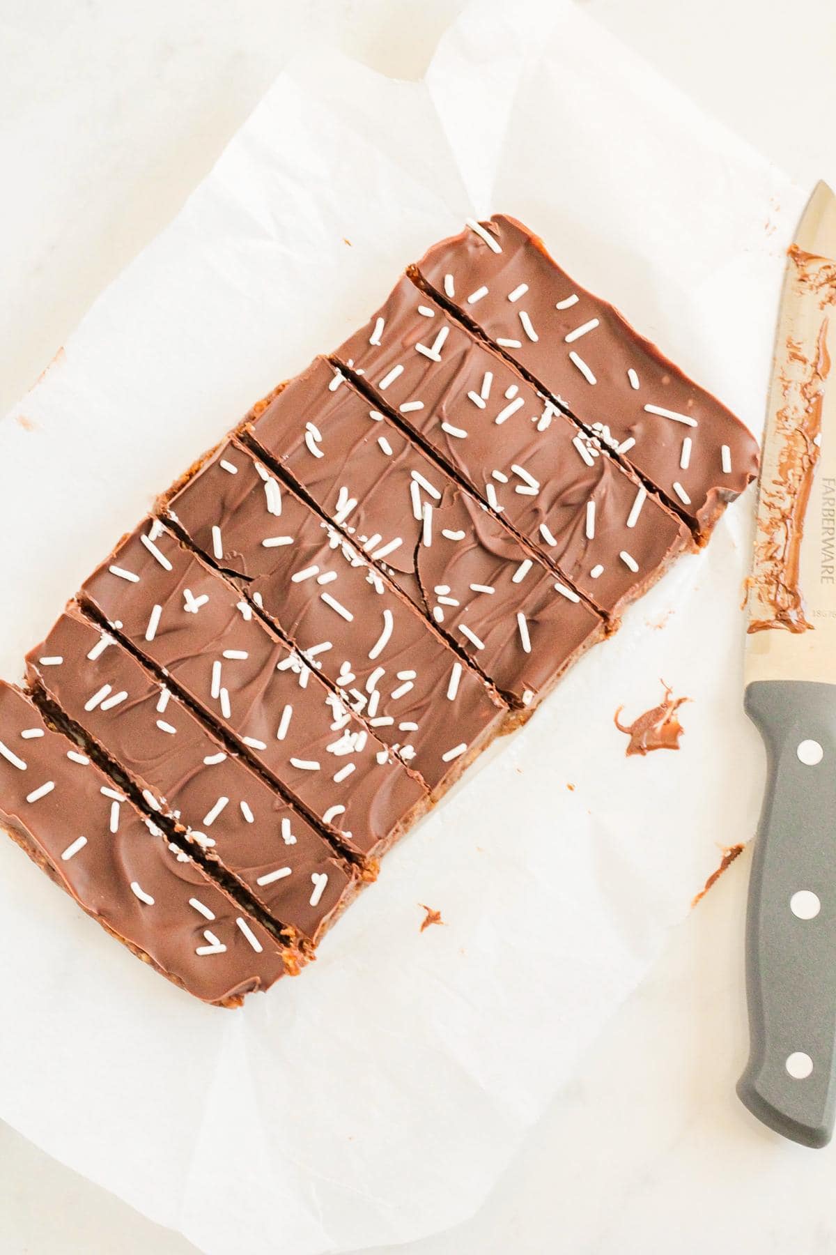 A pumpkin protein bar, accompanied by a knife, that has been cut into pieces. 