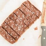 A pumpkin protein bar with sprinkles and a knife next to it.