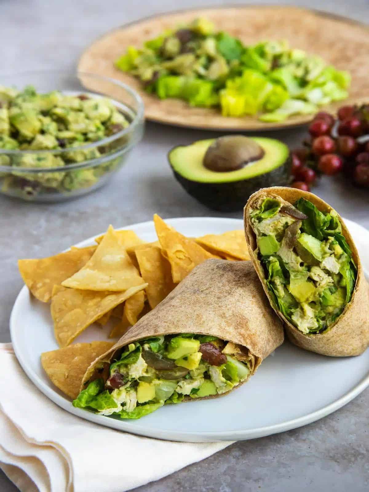 A avocado chicken salad \with guacamole and chips on a plate.