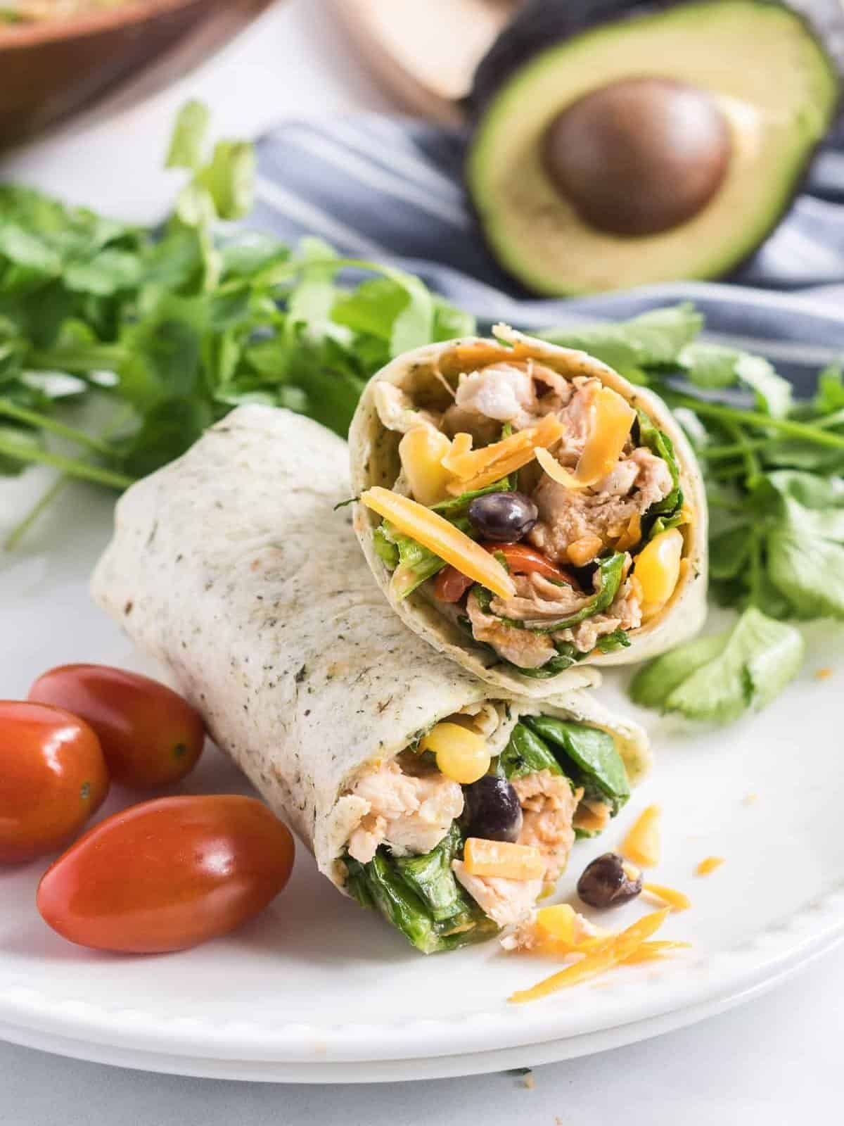 BBQ chicken salad wrap on a plate with lettuce and tomatoes.