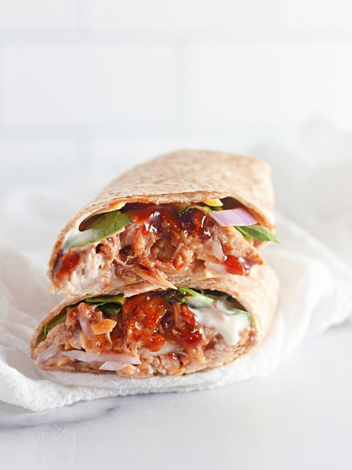 A healthy BBQ chicken wrap on a white napkin.