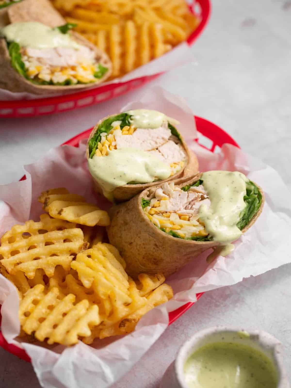 Chick-fil-a grilled chicken cool wraps drizzled with avocado lime ranch dressing and fries in a red basket.