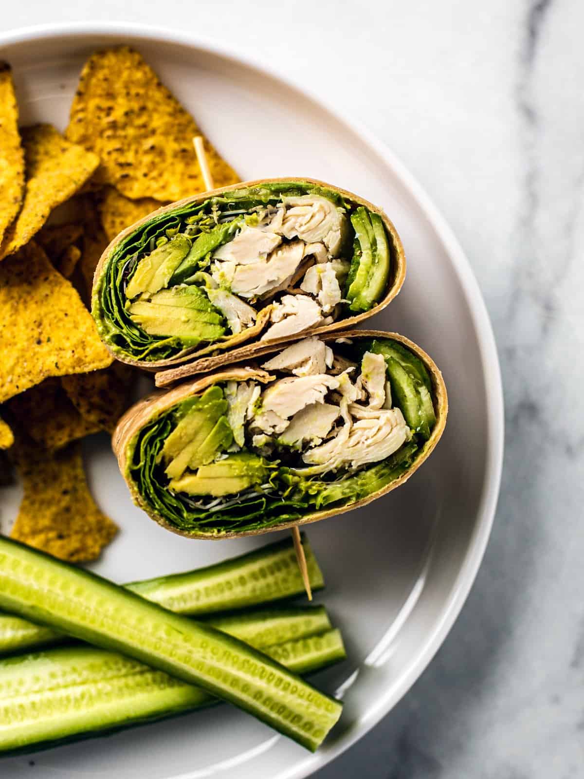 Green goddess chicken wraps with chips and cucumber on a plate.