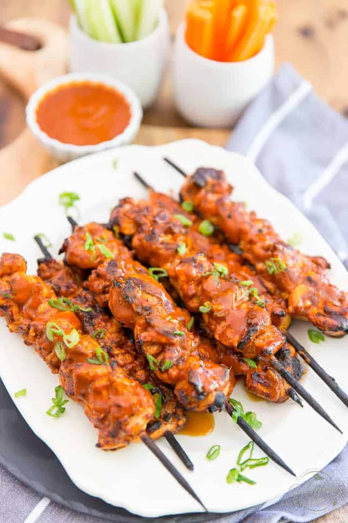 Buffalo chicken skewers with hot sauce on a plate.