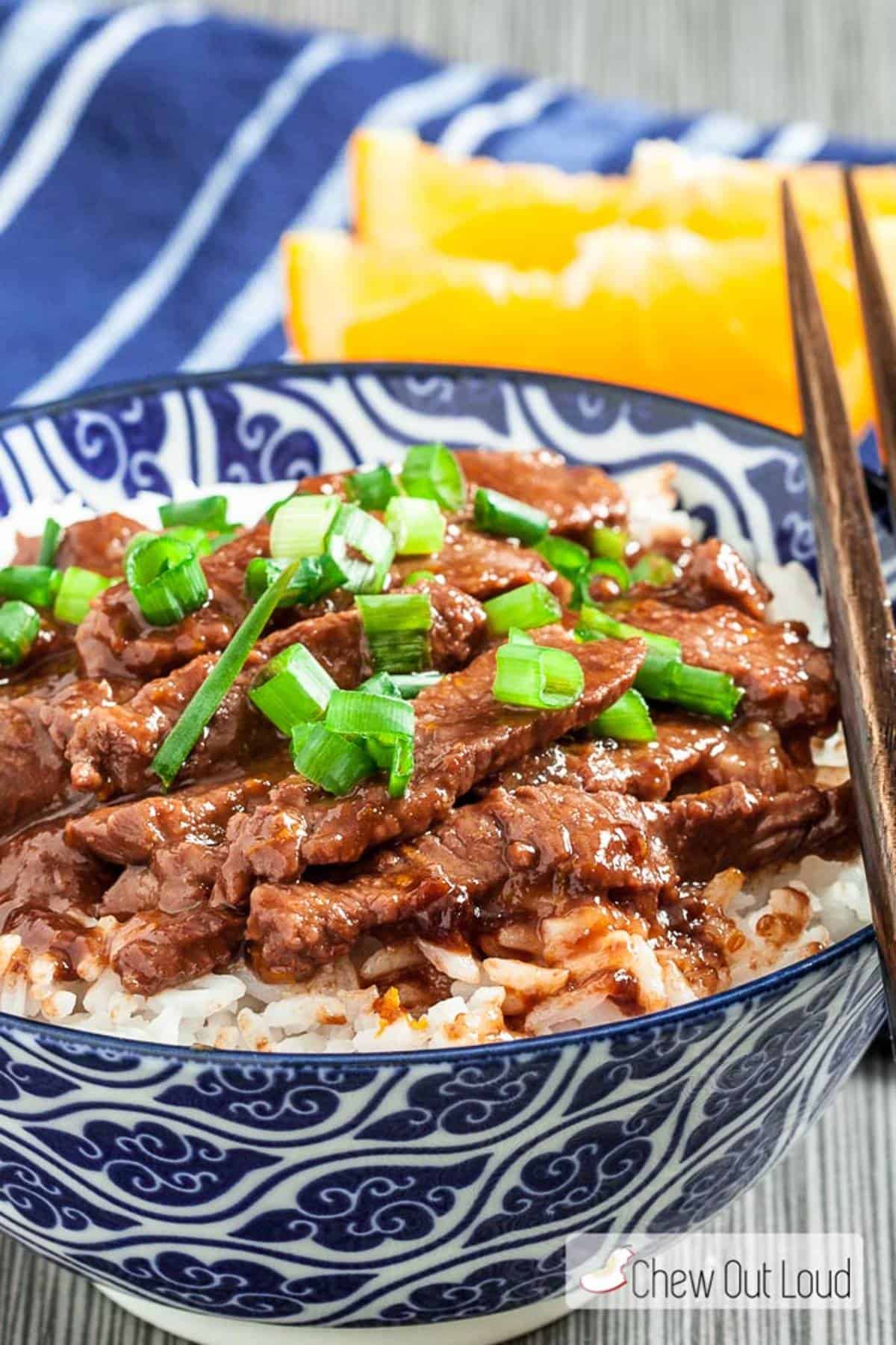 Orange beef and rice in a bowl with chopsticks.