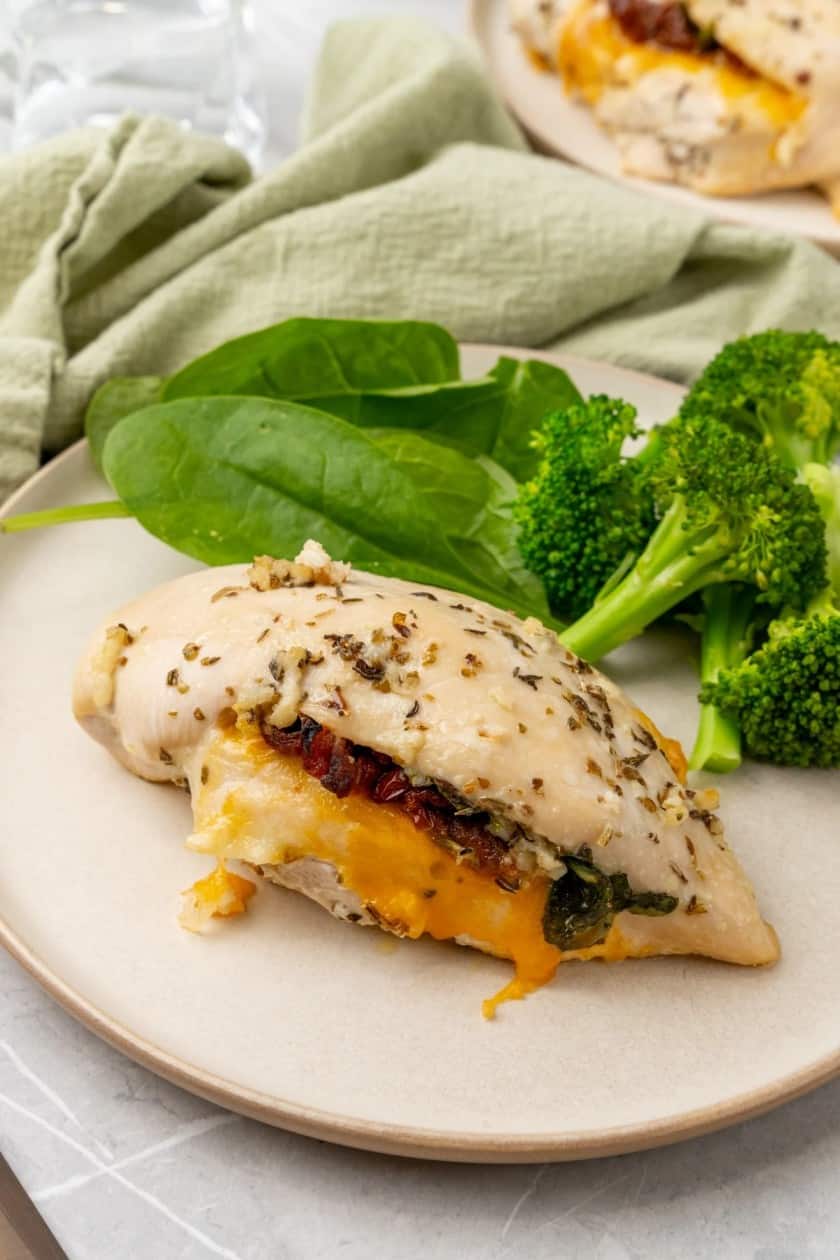 Stuffed chicken breast with broccoli and spinach on a plate.  
